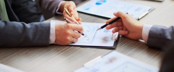 Discussing the scheme. Side view of business people, pointing handles on the chart together, sitting at the table